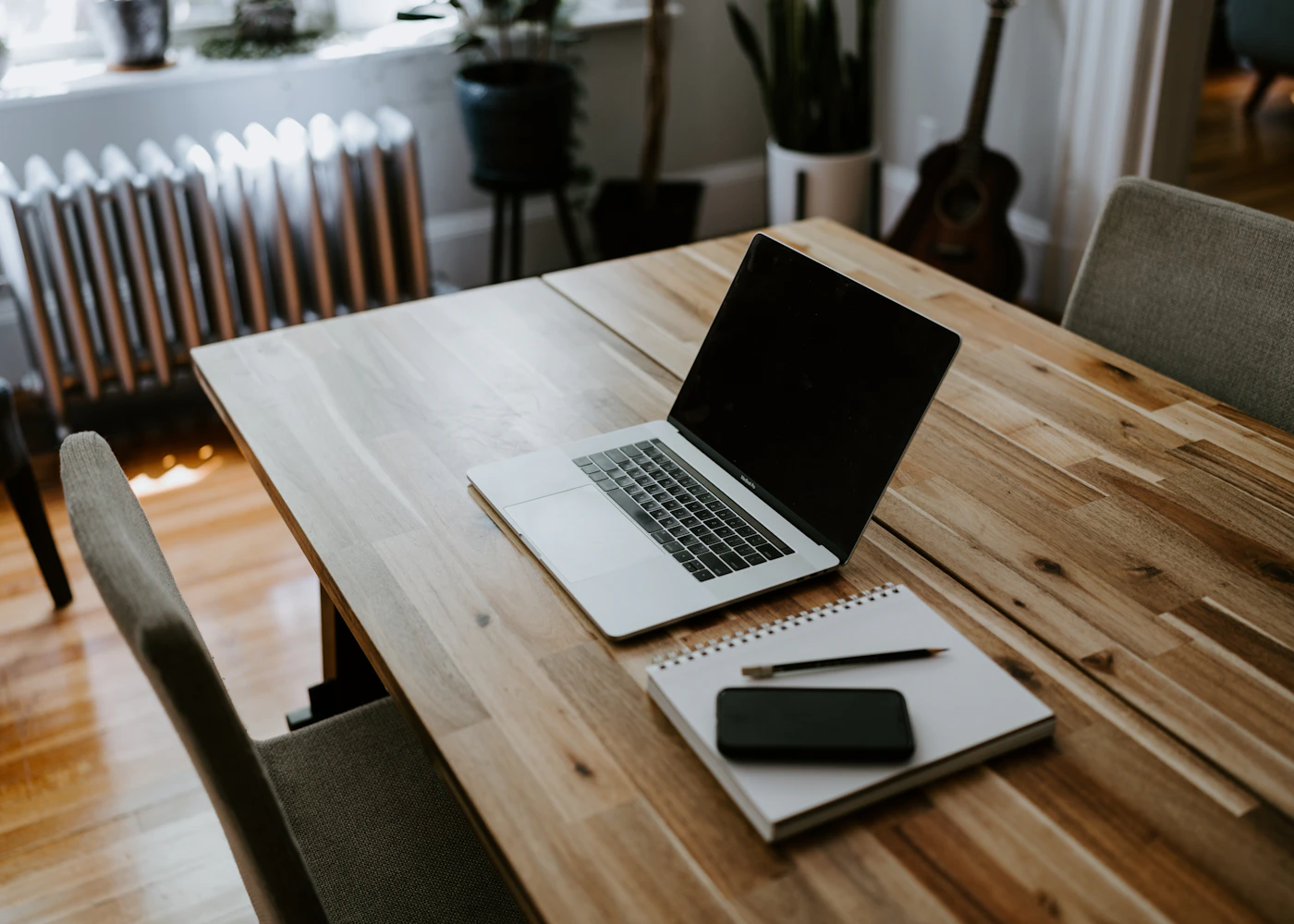 Simple home workspace with a laptop and notebook beside a window