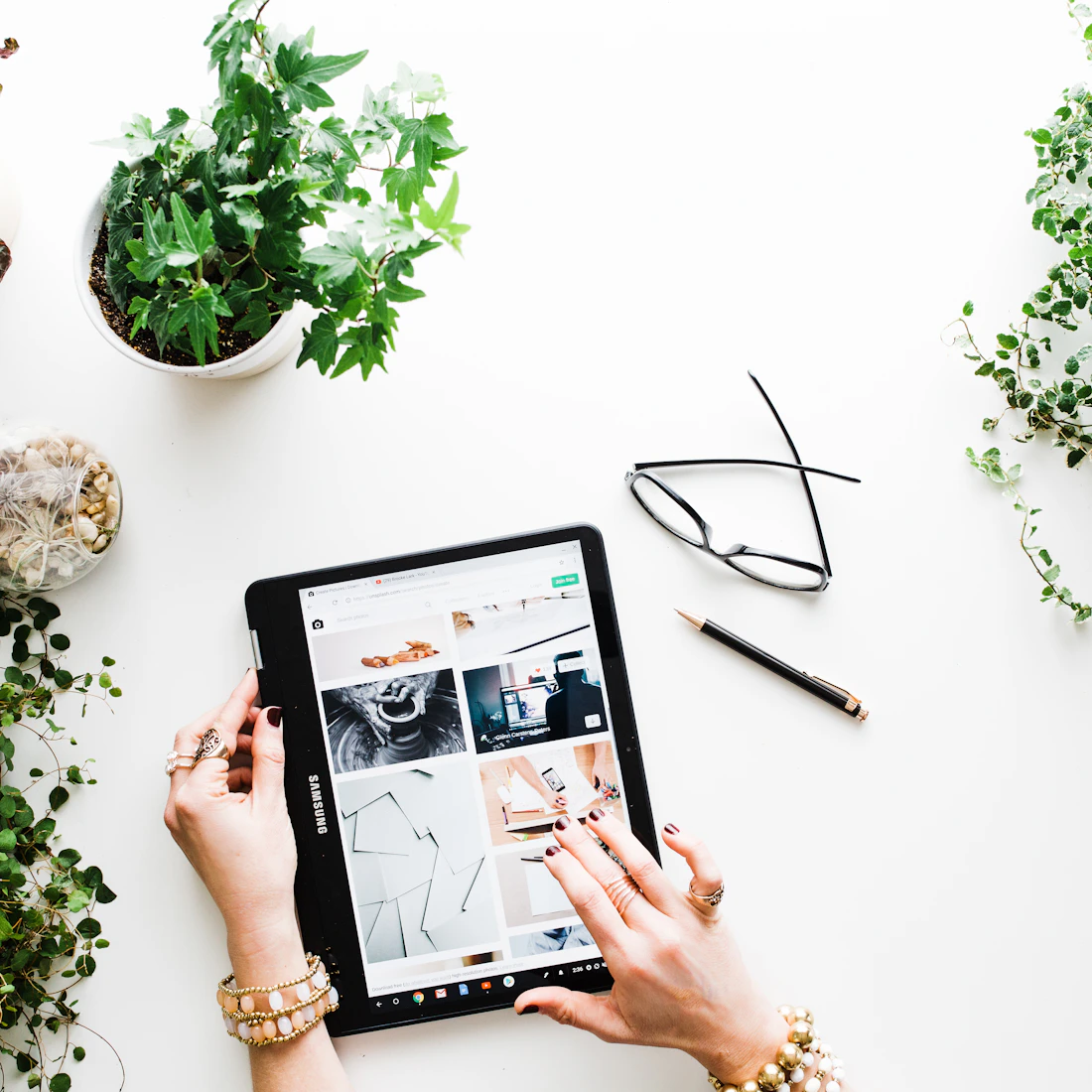 Hands browsing digital content on a tablet beside green plants